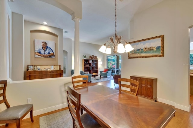 dining space featuring an inviting chandelier, arched walkways, baseboards, and light wood-type flooring