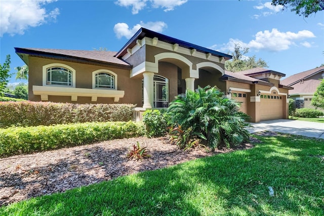 mediterranean / spanish house featuring concrete driveway, a garage, a front lawn, and stucco siding