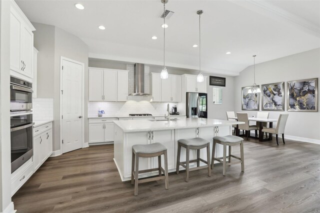 5477 Wayfarer Ave, Apollo Beach, FL 33572 - kitchen featuring wall chimney range hood, stainless steel appliances, decorative backsplash, recessed lighting, and a kitchen bar