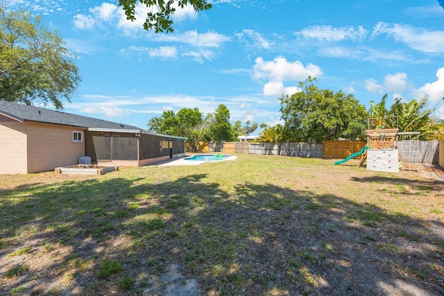 view of yard featuring a fenced backyard, a playground, and a sunroom