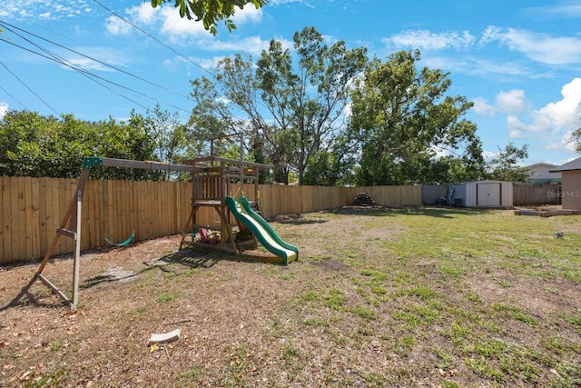 view of yard with a fenced backyard, an outbuilding, a playground, and a storage shed