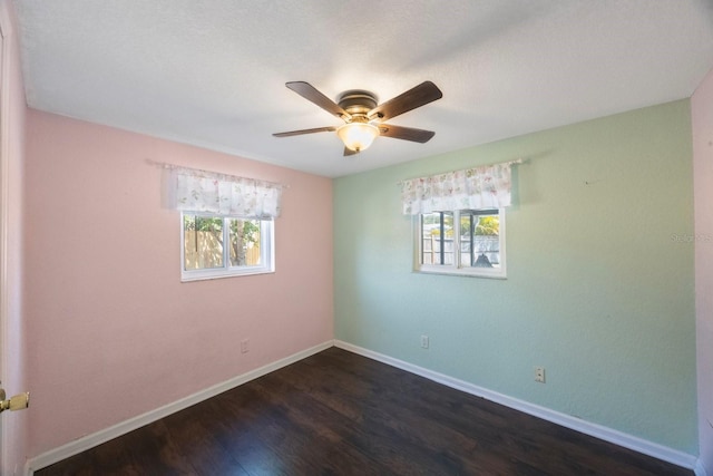 unfurnished room featuring baseboards, ceiling fan, dark wood-style flooring, and a wealth of natural light