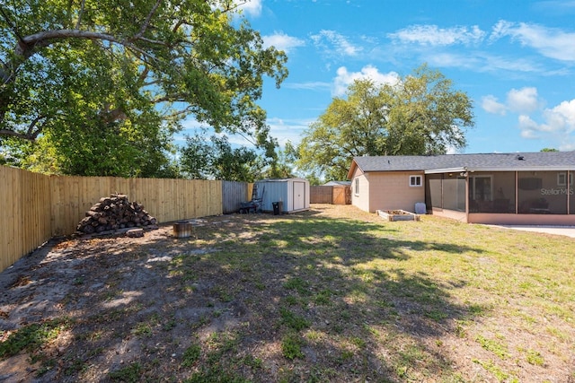 view of yard featuring a storage shed, an outdoor structure, a sunroom, and a fenced backyard