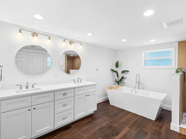 326 176th Avenue Cir, Redington Shores, FL 33708 - bathroom with double vanity, a freestanding bath, wood finished floors, baseboards, and recessed lighting