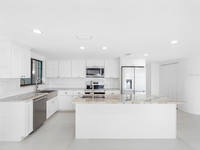 326 176th Avenue Cir, Redington Shores, FL 33708 - kitchen with stainless steel appliances, a sink, an island with sink, decorative backsplash, and light stone countertops