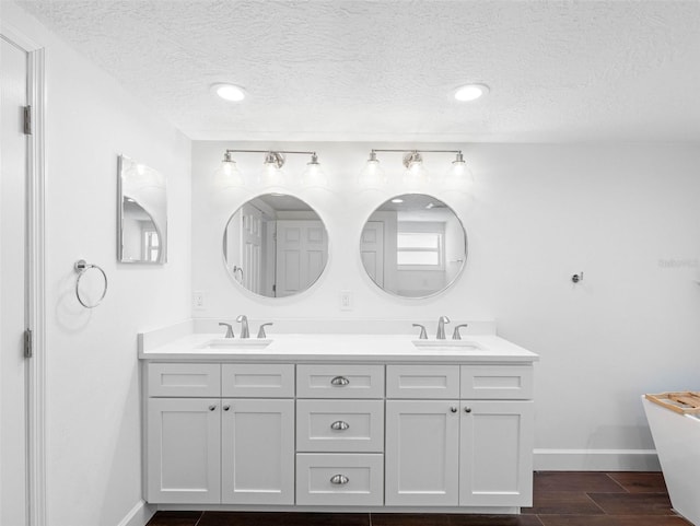 326 176th Avenue Cir, Redington Shores, FL 33708 - full bath with double vanity, baseboards, a textured ceiling, a soaking tub, and wood finished floors