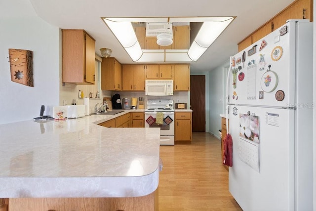 7534 Culberson Dr, Port Richey, FL 34668 - kitchen featuring a sink, white appliances, light countertops, light wood-style flooring, and a peninsula