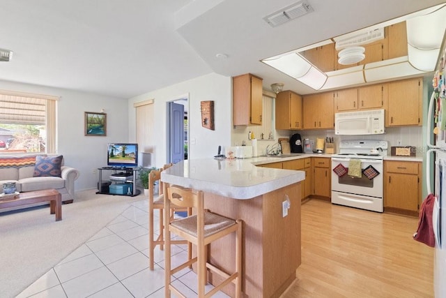 7534 Culberson Dr, Port Richey, FL 34668 - kitchen featuring a breakfast bar area, visible vents, light countertops, a peninsula, and white appliances