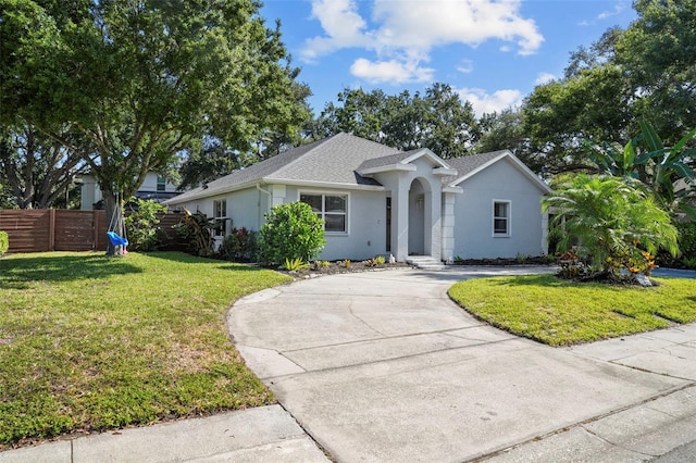 ranch-style home featuring fence, a shingled roof, stucco siding, a front yard, and driveway