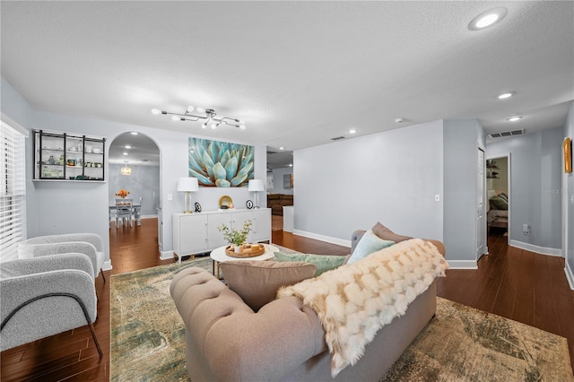 living room featuring visible vents, arched walkways, wood finished floors, baseboards, and recessed lighting