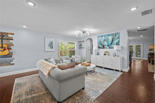 living area with visible vents, arched walkways, a textured ceiling, and dark wood-style floors