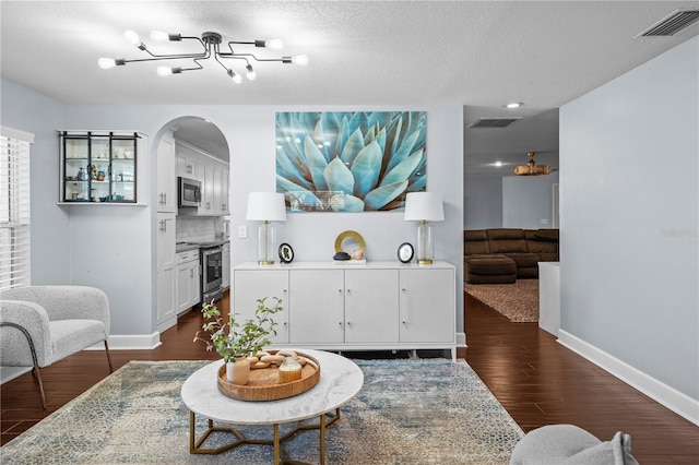 living room with an inviting chandelier, arched walkways, baseboards, and dark wood-type flooring
