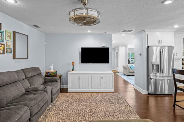 living room with dark wood finished floors, a textured ceiling, and visible vents