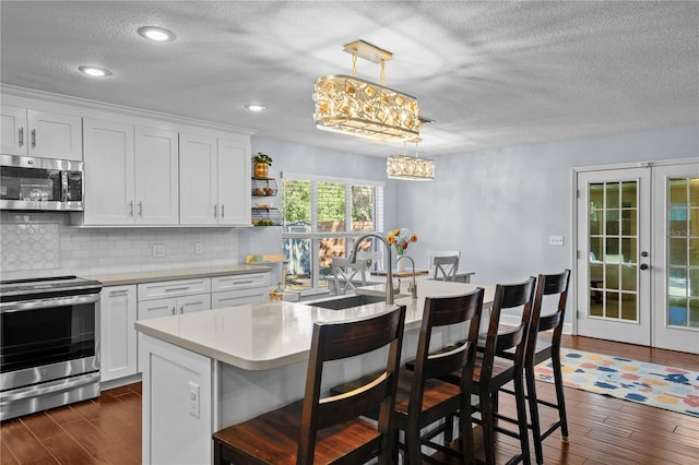 kitchen with french doors, a textured ceiling, appliances with stainless steel finishes, tasteful backsplash, and a sink
