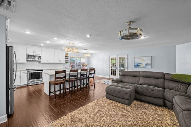 living area with visible vents, recessed lighting, a textured ceiling, and a chandelier