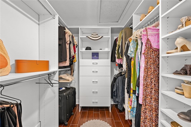 spacious closet with attic access and dark wood-style floors