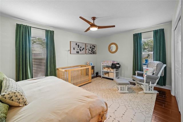 bedroom featuring a ceiling fan, baseboards, wood finished floors, and a closet