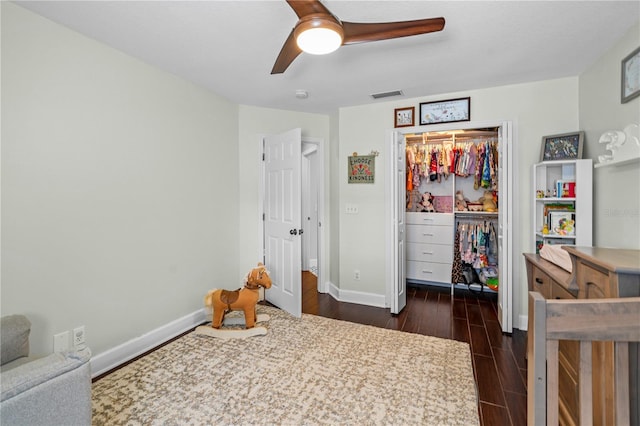 bedroom with baseboards, dark wood-type flooring, visible vents, and a closet