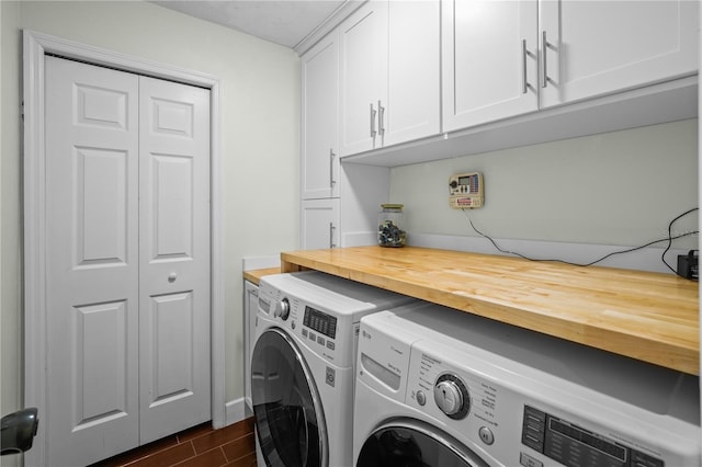washroom featuring baseboards, wood finish floors, cabinet space, and washer and clothes dryer