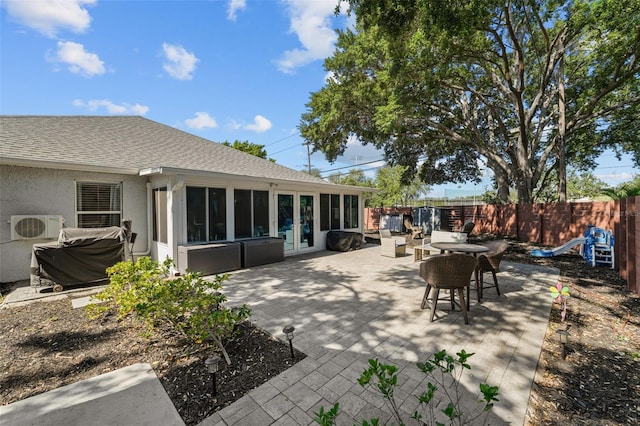 view of patio / terrace featuring outdoor dining area, ac unit, a fenced backyard, and a sunroom