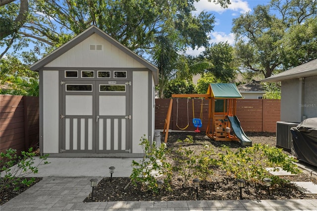 view of shed with a fenced backyard, central air condition unit, and a playground
