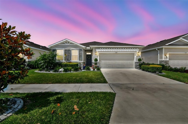 view of front of home with an attached garage, stone siding, stucco siding, a front yard, and concrete driveway
