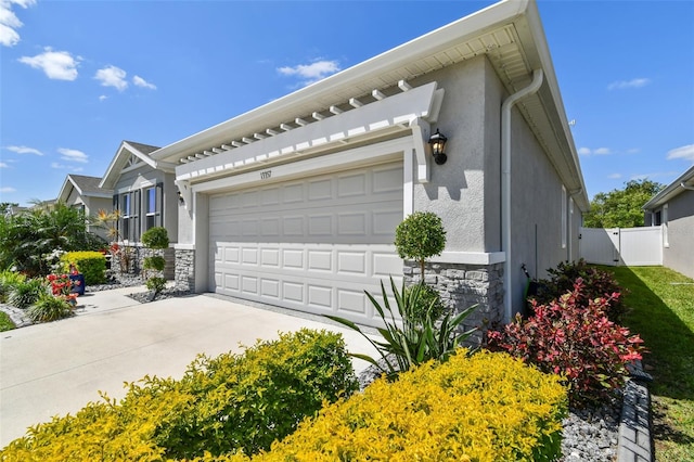 view of home's exterior featuring fence, stucco siding, driveway, and stone siding