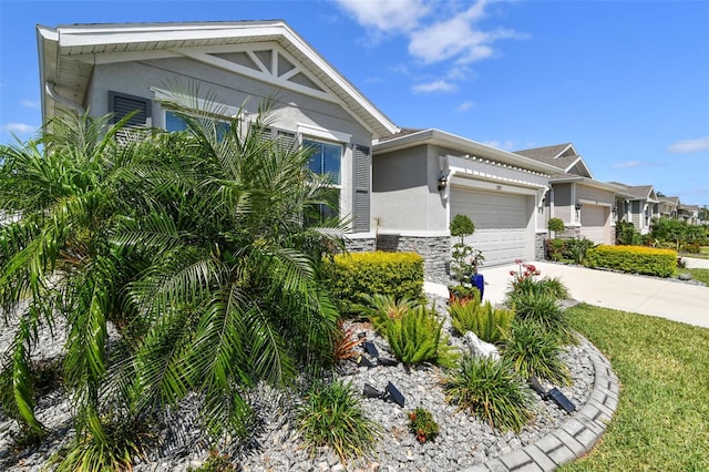 view of front of house featuring a garage, stucco siding, driveway, and stone siding