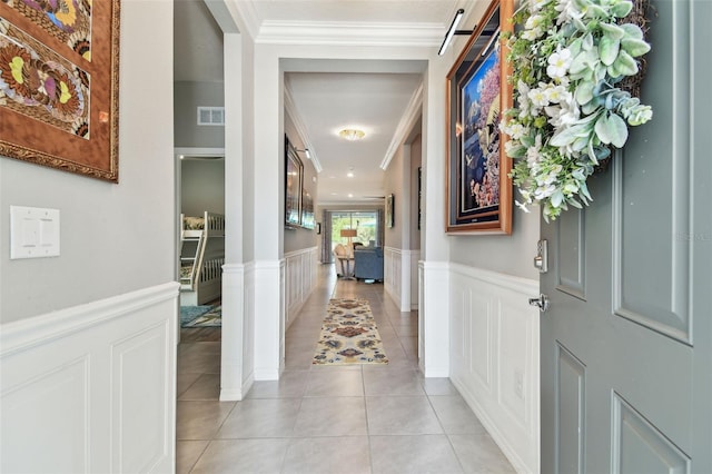 hallway with visible vents, decorative columns, light tile patterned floors, and a wainscoted wall