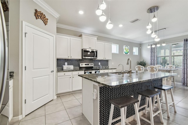 kitchen featuring a kitchen bar, visible vents, a sink, ornamental molding, and stainless steel appliances