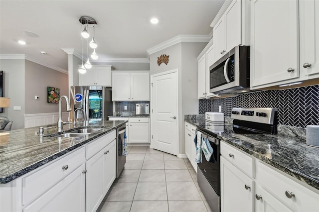 kitchen with a sink, stainless steel appliances, white cabinetry, tasteful backsplash, and ornamental molding