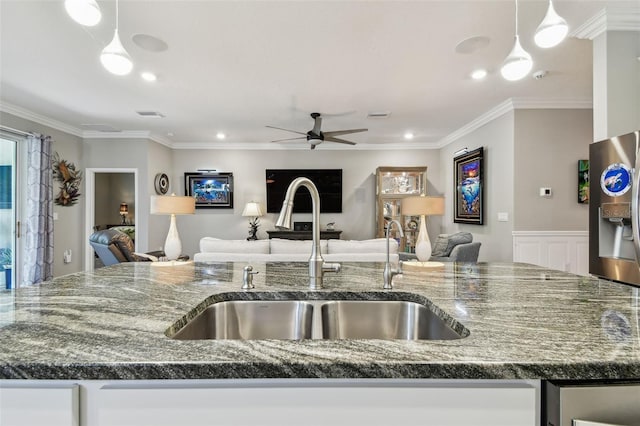 kitchen featuring ceiling fan, a sink, open floor plan, stainless steel refrigerator with ice dispenser, and ornamental molding