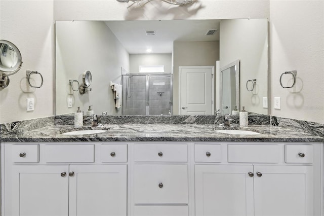 full bath featuring double vanity, visible vents, a shower stall, and a sink