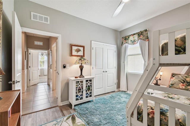bedroom featuring a ceiling fan, visible vents, baseboards, a closet, and light wood-style floors
