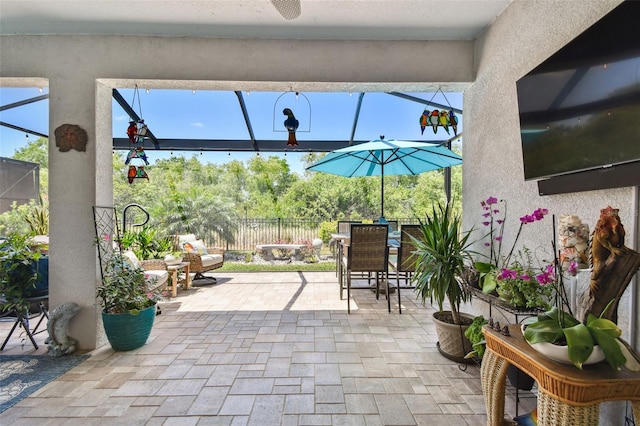 view of patio / terrace featuring glass enclosure, fence, and outdoor dining area