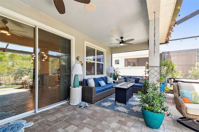 view of patio / terrace with ceiling fan and an outdoor living space with a fire pit