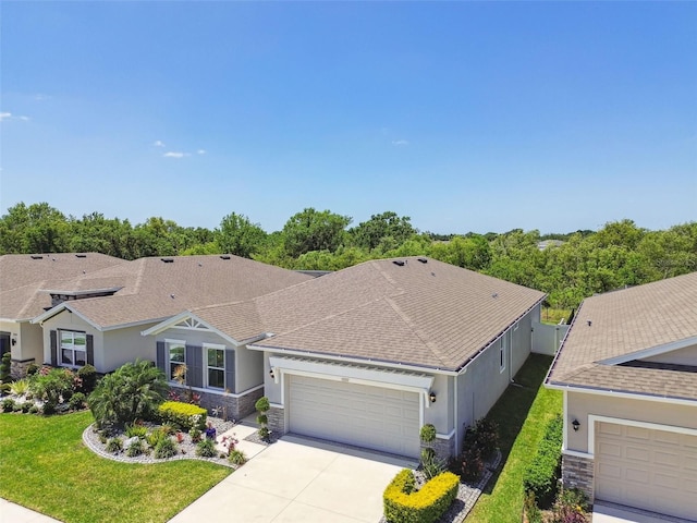 single story home with concrete driveway, an attached garage, stone siding, and stucco siding
