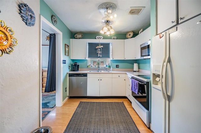 5101 13th Ave S, Gulfport, FL 33707 - kitchen featuring light wood-type flooring, light countertops, white cabinets, a sink, and stainless steel appliances