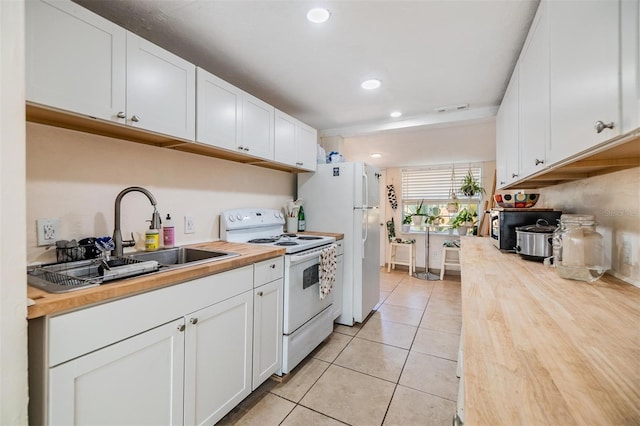 5101 13th Ave S, Gulfport, FL 33707 - kitchen with butcher block countertops, a sink, white cabinets, white appliances, and light tile patterned flooring