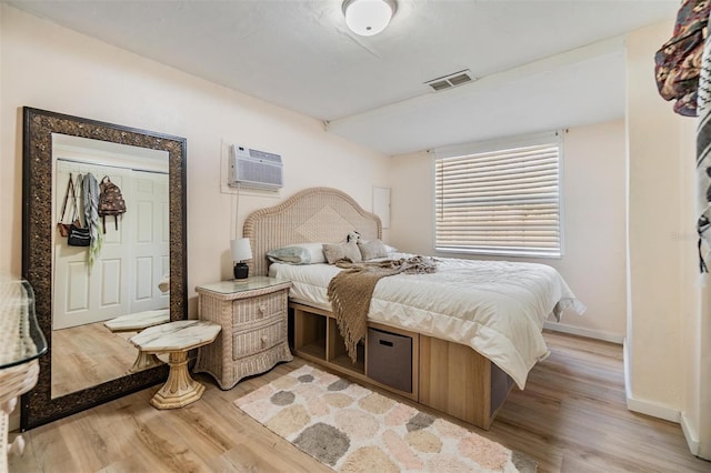 5101 13th Ave S, Gulfport, FL 33707 - bedroom featuring visible vents, a wall mounted air conditioner, light wood finished floors, and baseboards