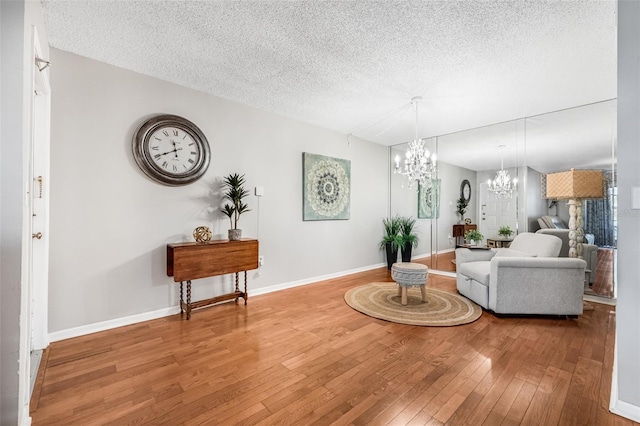 1281 Pine Ridge Cir E Unit H1, Tarpon Springs, FL 34688 - living room with a textured ceiling, an inviting chandelier, baseboards, and hardwood / wood-style flooring