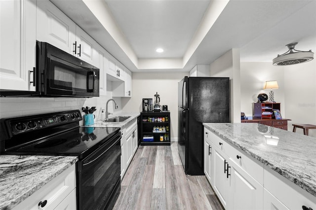 710 N Village Dr N Unit 102, Saint Petersburg, FL 33716 - kitchen with black appliances, white cabinets, light stone countertops, light wood-style flooring, and recessed lighting