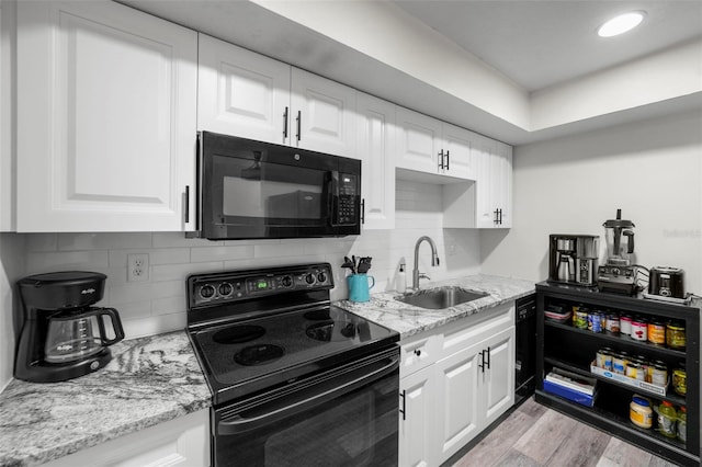 710 N Village Dr N Unit 102, Saint Petersburg, FL 33716 - kitchen with black appliances, a sink, and white cabinets