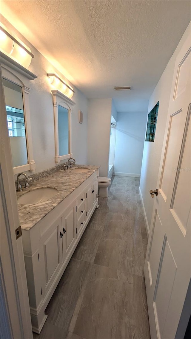4872 Silverthorne Ct, Oldsmar, FL 34677 - bathroom with toilet, a textured ceiling, double vanity, and baseboards