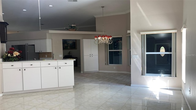 kitchen featuring an inviting chandelier, marble finish floor, freestanding refrigerator, white cabinetry, and ornamental molding