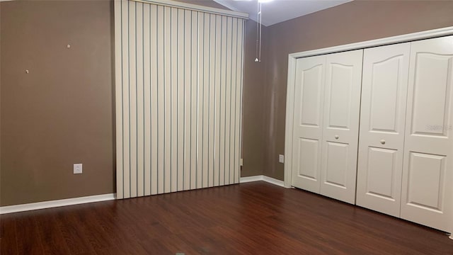 unfurnished bedroom with baseboards, dark wood finished floors, and a closet