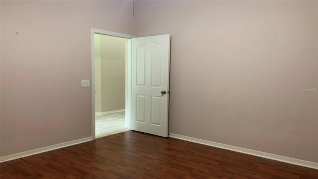 spare room with baseboards and wood finished floors