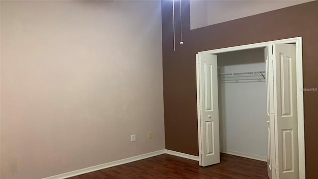 unfurnished bedroom with baseboards, dark wood finished floors, and a closet