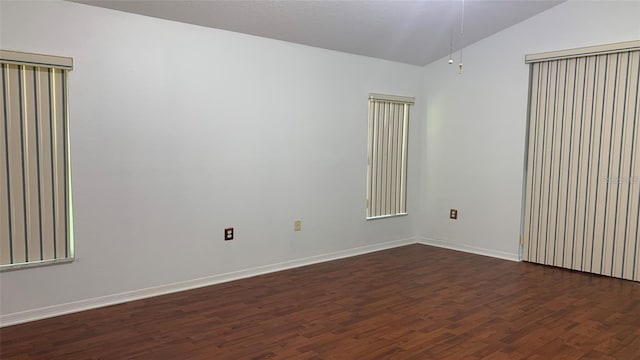unfurnished room with baseboards, ceiling fan, vaulted ceiling, and dark wood-type flooring