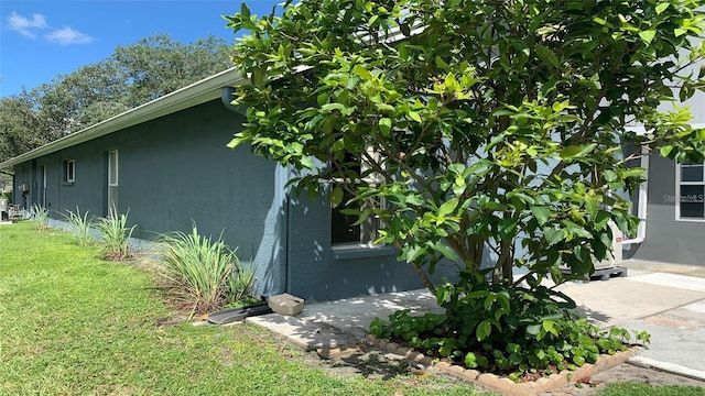 view of side of property with a lawn and stucco siding
